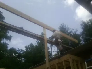 Carpenter setting a ridge beam over a new addition frame — Ice Dam Removal by Roofing Brothers in Keller
