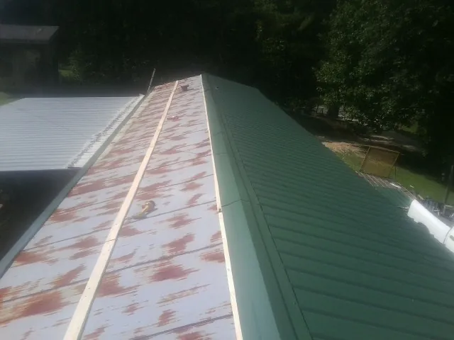 Old rusted panels beside newly installed green metal roofing — Wind Damage Roof Repair by Roofing Brothers in Keller