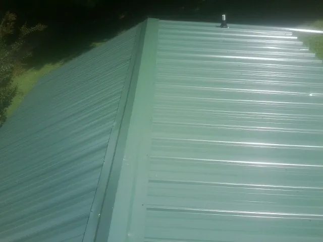 New green metal panels meeting at the ridge of a roof — Flat Roof Repair work by our crew in Keller