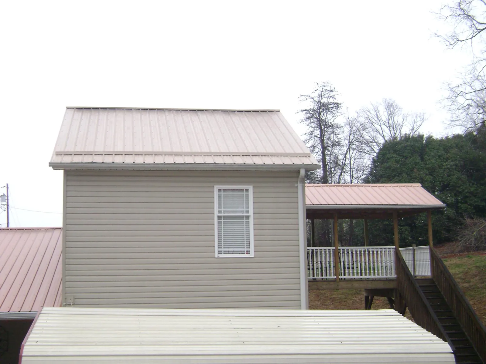 Tan metal roofs on a two story addition and attached porch, from a Roof Replacement job in Keller