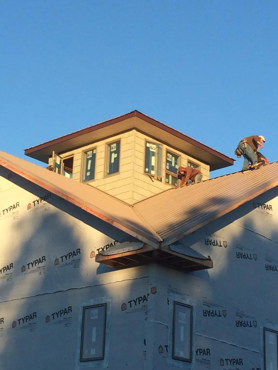 Roofers working around a rooftop cupola on a new metal roof at sunset — Roof Waterproofing in Keller by Roofing Brothers
